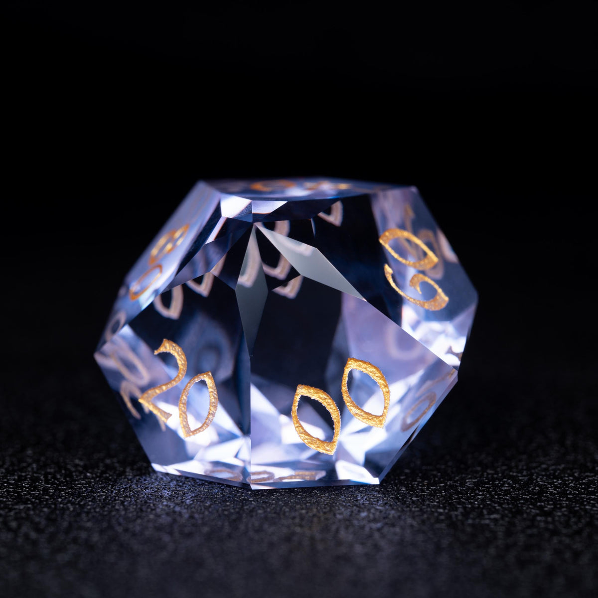 Faceted blue-violet clear percentile d10 die with gold numbers 20, 00 and 60, on a dark sparkly surface