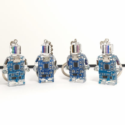 Four blue circuit board robot keychains with clear bodies and striped heads in a row on a white background